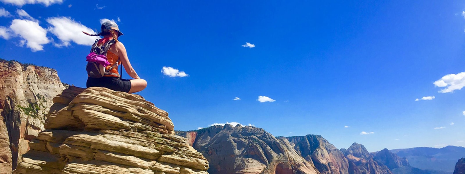 Woman sitting on rock looking out at sky