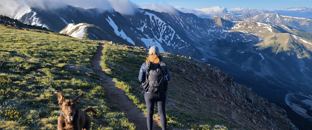 woman hiking through an alpine terrain with a dog